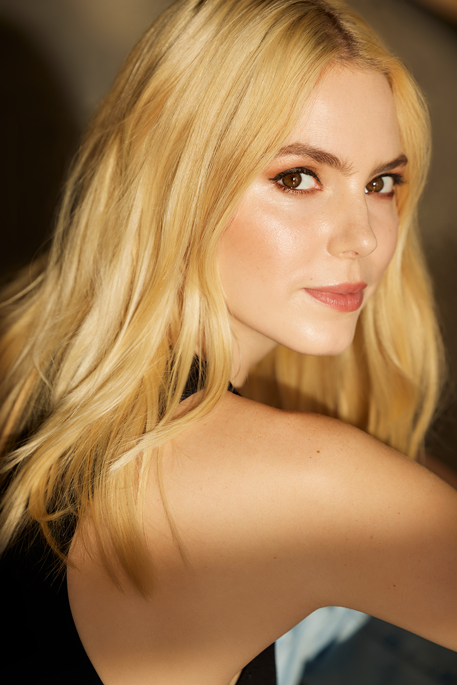 Alyson Gorske in a side-profile portrait with loose blonde hair, glancing back toward the camera in warm light.